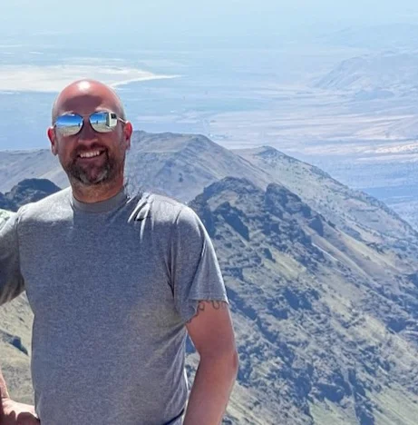 man pictured in front of mountains